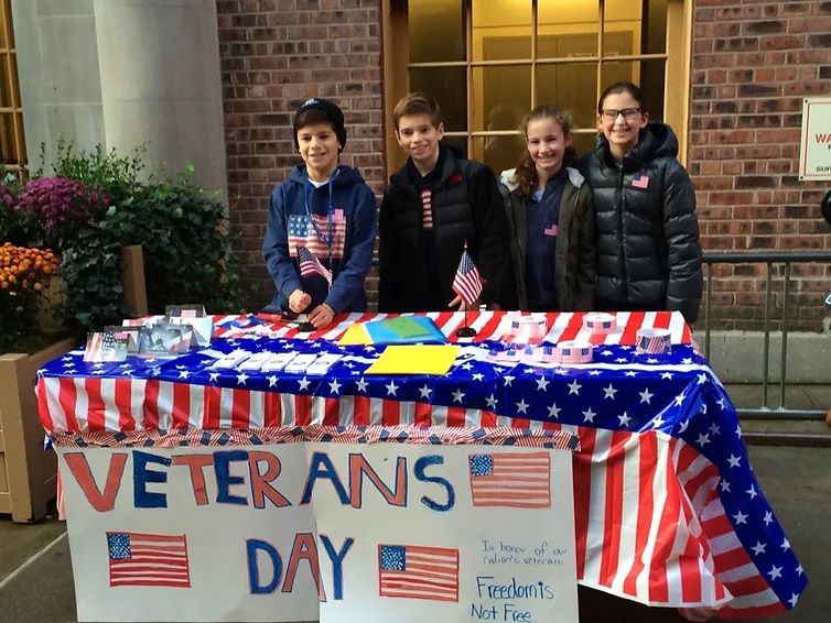 Four young volunteers at a Veterans Day booth.