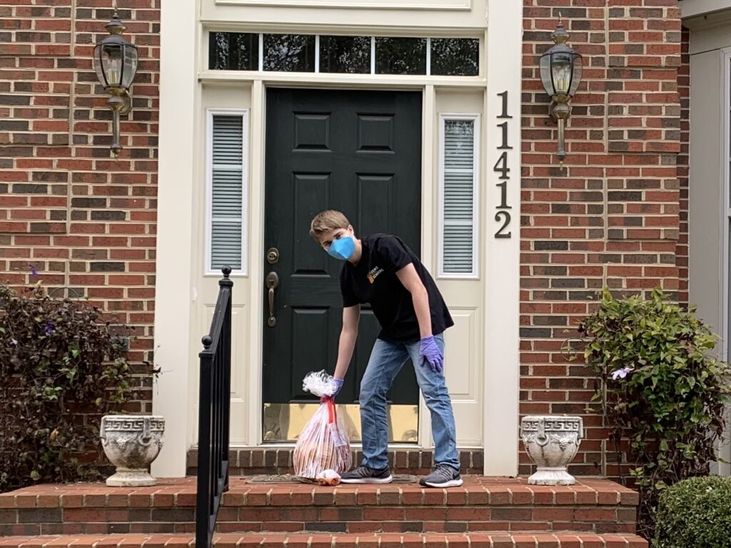 Matthew setting a bag of groceries on a doorstep.