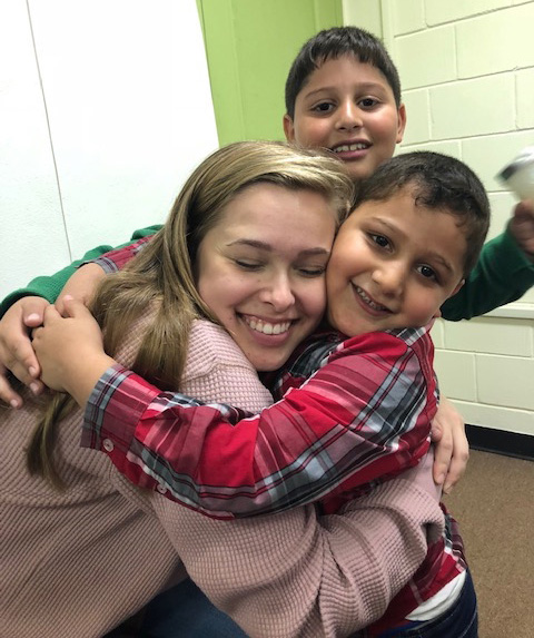 Grace hugging two boys in school.