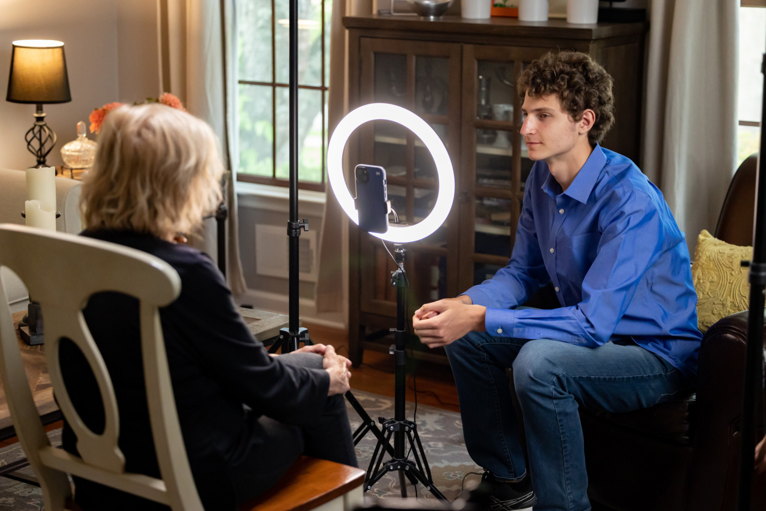 Using a cell phone and light on a tripod, Aron Goodman interviews his grandmother Tova Friedman for TovaTok.