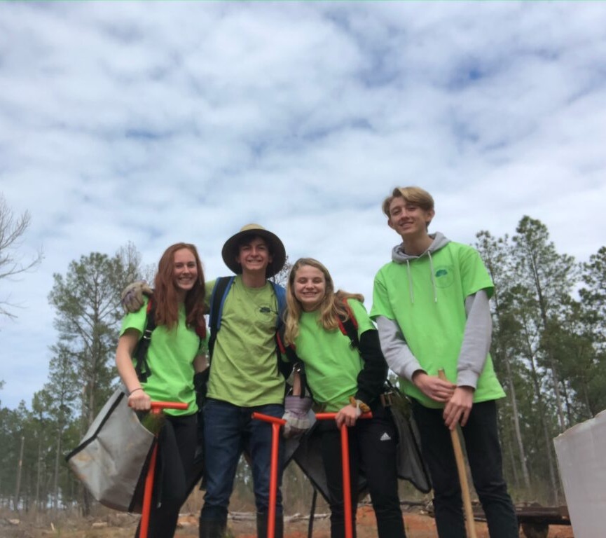 Evan and three other teens standing outside ready to plant trees.