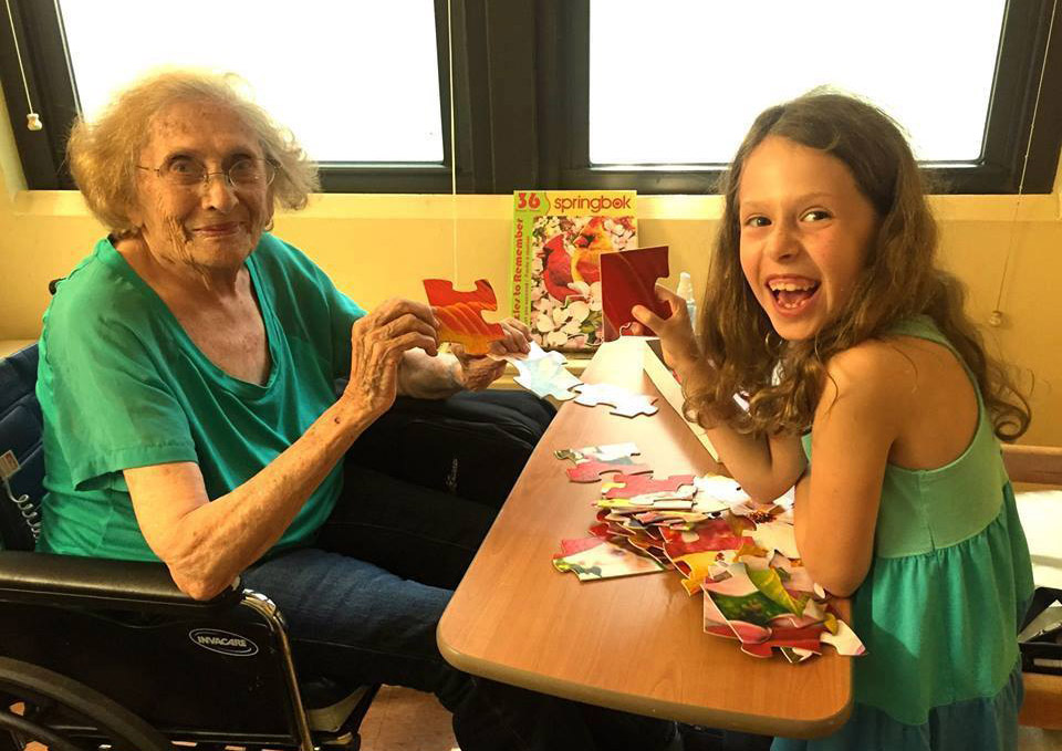 Hailey Richman as a young child sitting with her grandmother working on a puzzle.