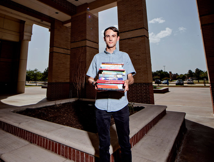 Cameron standing outside holding a stack of banned books.