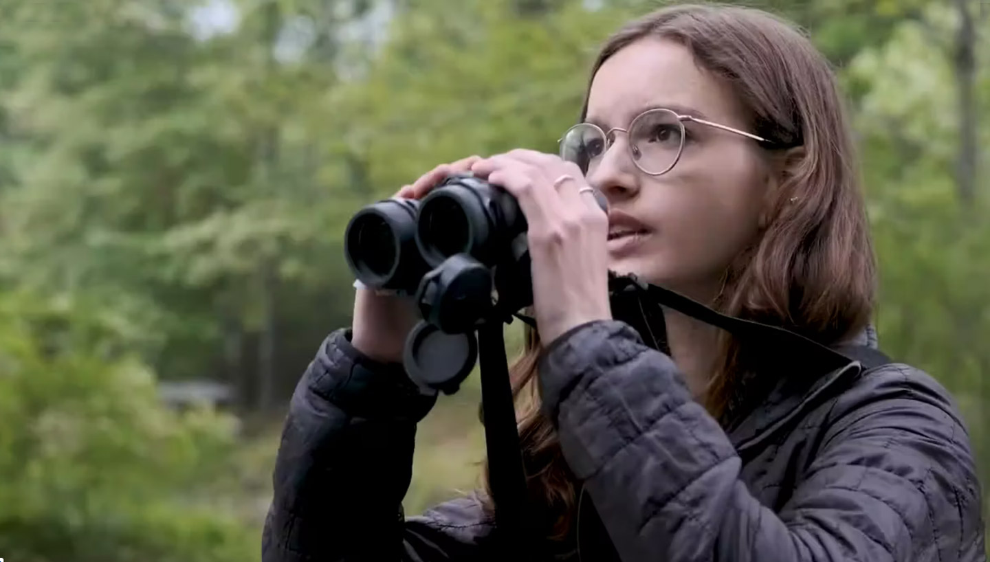 Anna holds up a pair of binoculars.