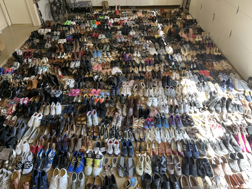 Overhead shot of hundreds of pairs of shoes lined up in a garage.