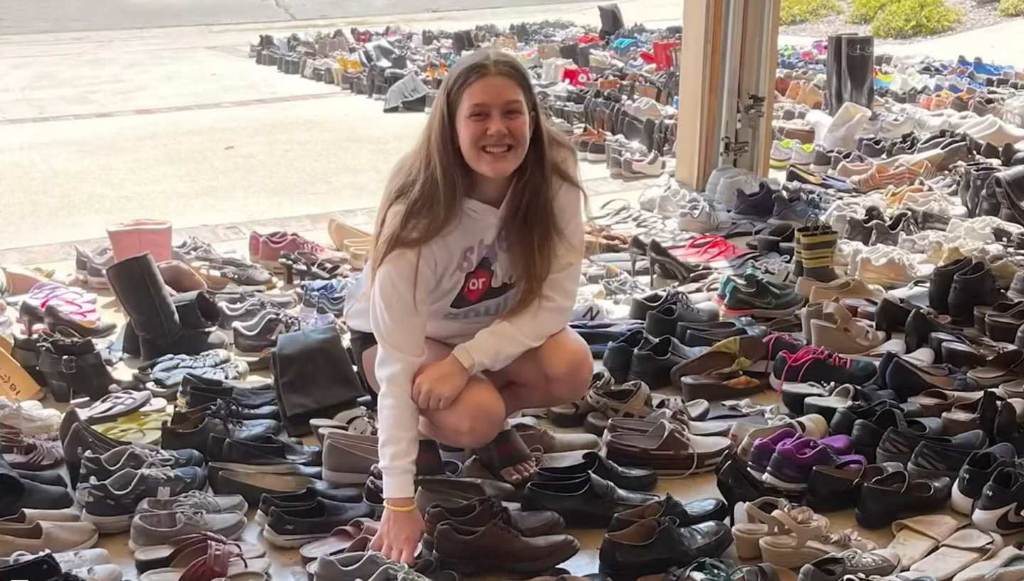 Lindsay squatting down in her garage amongst hundreds of pairs of shoes.