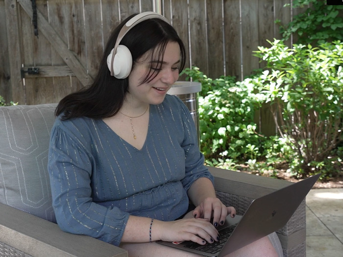 Lauren sitting outside working on her laptop with headphones on.