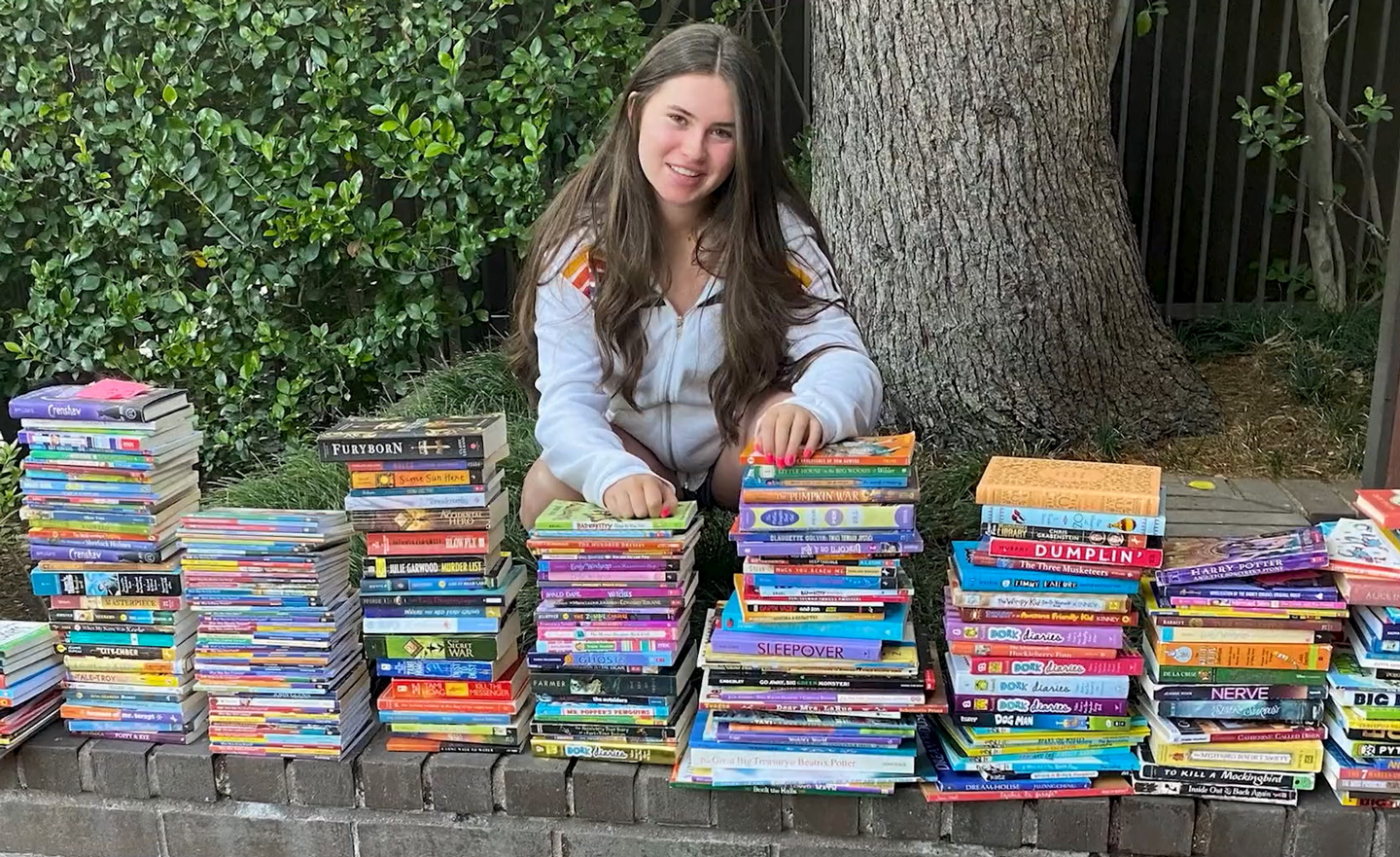 Alana poses with several stacks of books.