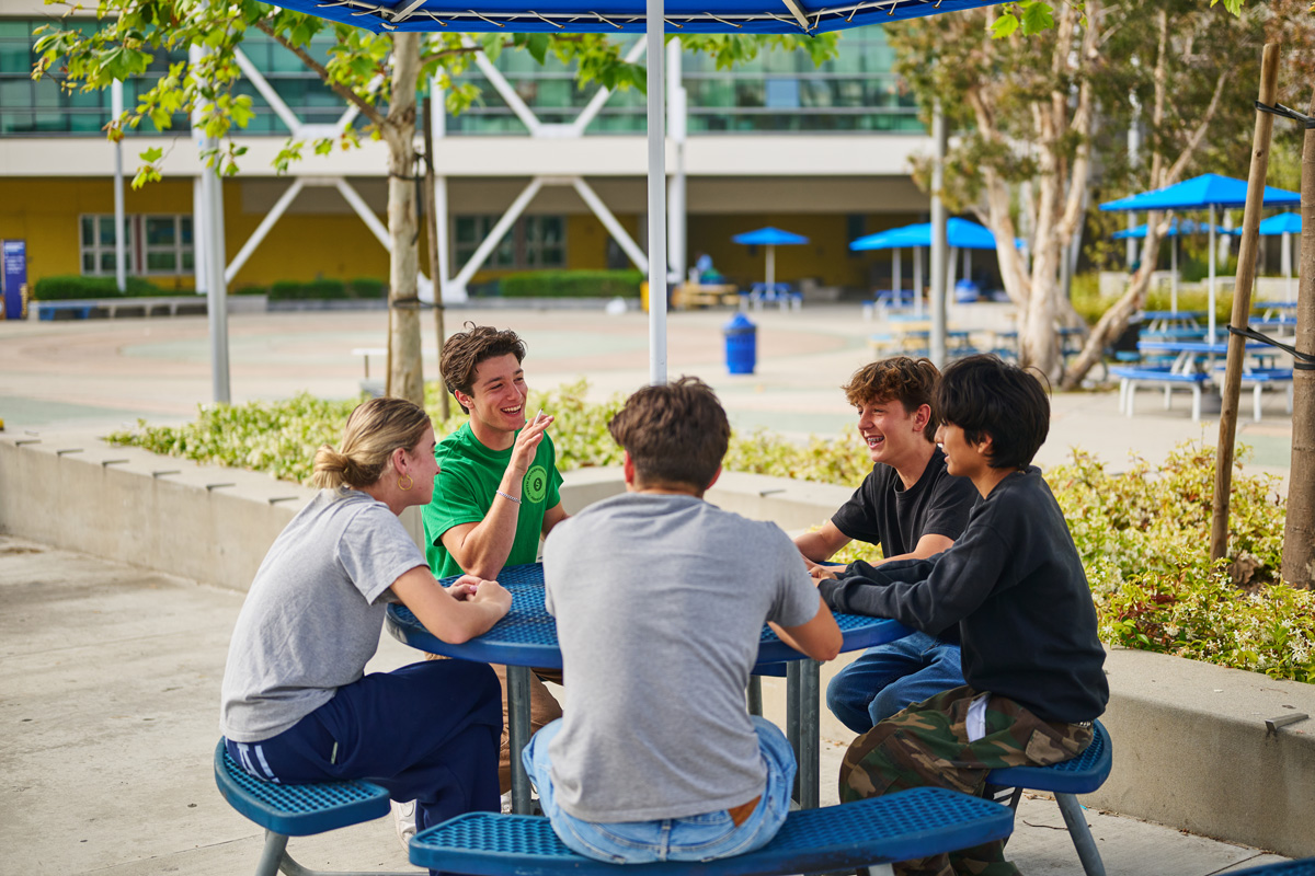 Mason Arditi sits outside at a round table with four other students.