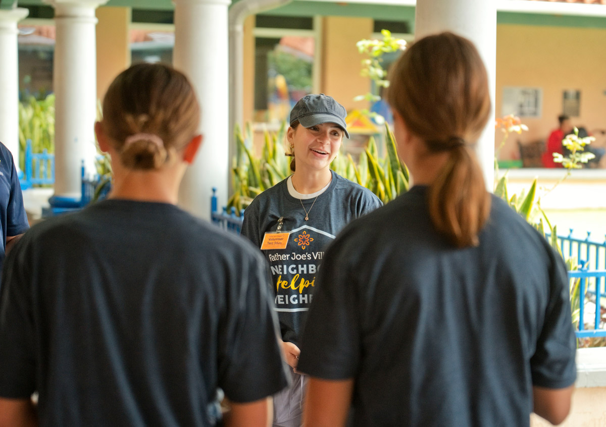 Volunteers in matching shirts talk outside a building during a community service event.