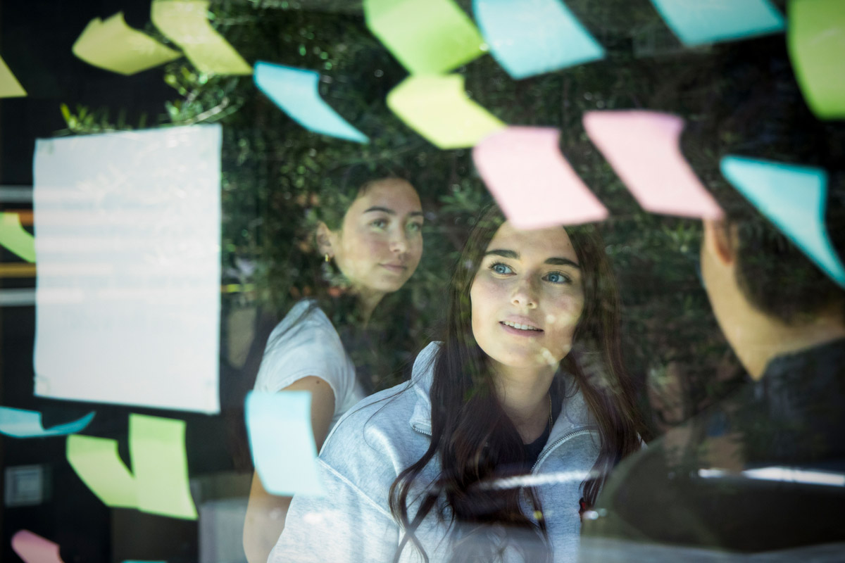 Person looks out a glass window covered in colorful sticky notes during a collaborative meeting.